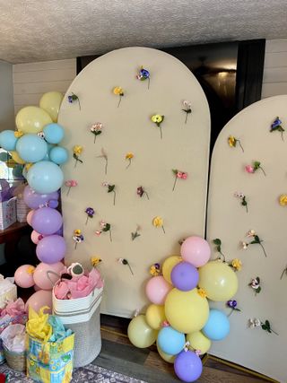 Pastel floral arch backdrop with balloon garland and gift baskets