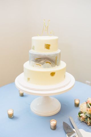 Two-tier wedding cake with gold leaf and marbled middle tier