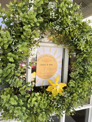 Sunshine-themed baby shower wreath with party invitation