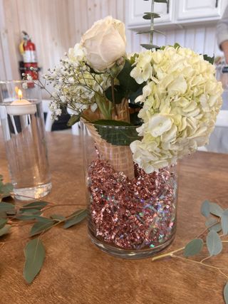 Cream rose centerpiece in a confetti-filled glass vase