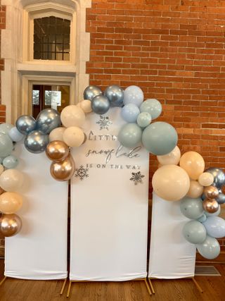 Winter baby shower balloon arch with snowflake backdrop